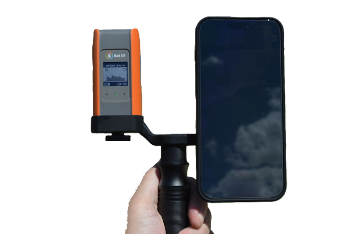 Hand holding a device with an orange and gray panel next to a smartphone on a white background